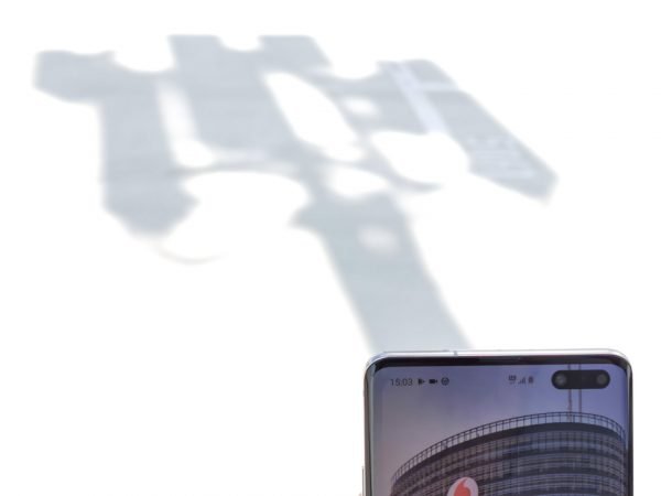 Ein 5G-Smartphone vor dem Schatten eines Funkmastes