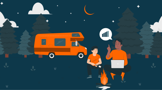 Ein Wohnmobil im Hintergrund und zwei Personen, die am Lagerfeuer sitzen und einen Laptop auf dem Schoß haben.