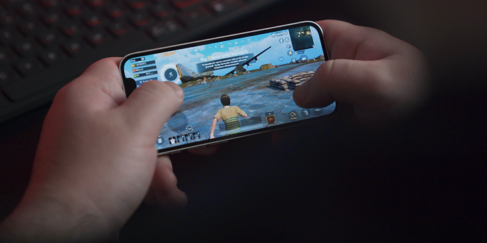 Jemand hält ein iPhone in beiden Händen und spielt ein Online-Game.