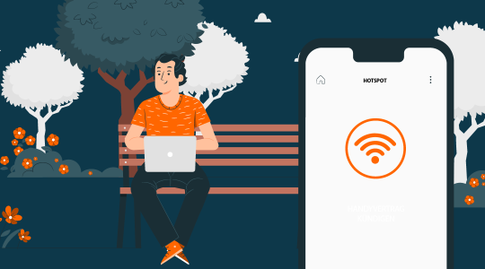 Ein Mann sitzt auf einer Bank im Park und arbeitet an seinem Laptop. Im Vordergrund ist ein Smartphone zu sehen, auf dessen Display das WLAN-Symbol erscheint.