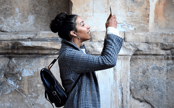 Eine Frau fotografiert mit ihrem Smartphone: Jederzeit Eindrücke teilen zu können, zählt zu den Vorzügen des Handys.