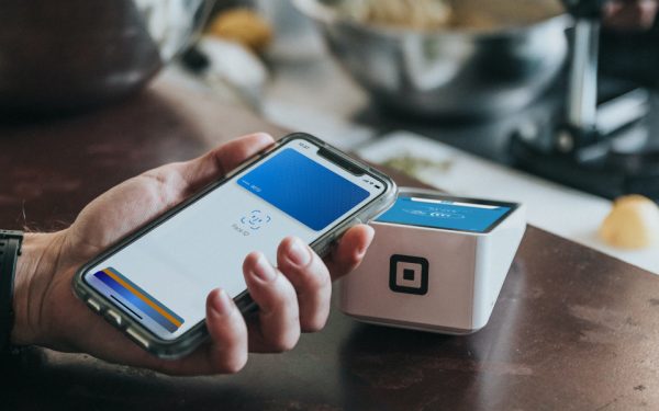 Bezahlen mit Apple Pay Bezahlen im Café: Jemand hält sein iPhone ans Kassenterminal und autorisiert via Face ID die Transaktion.