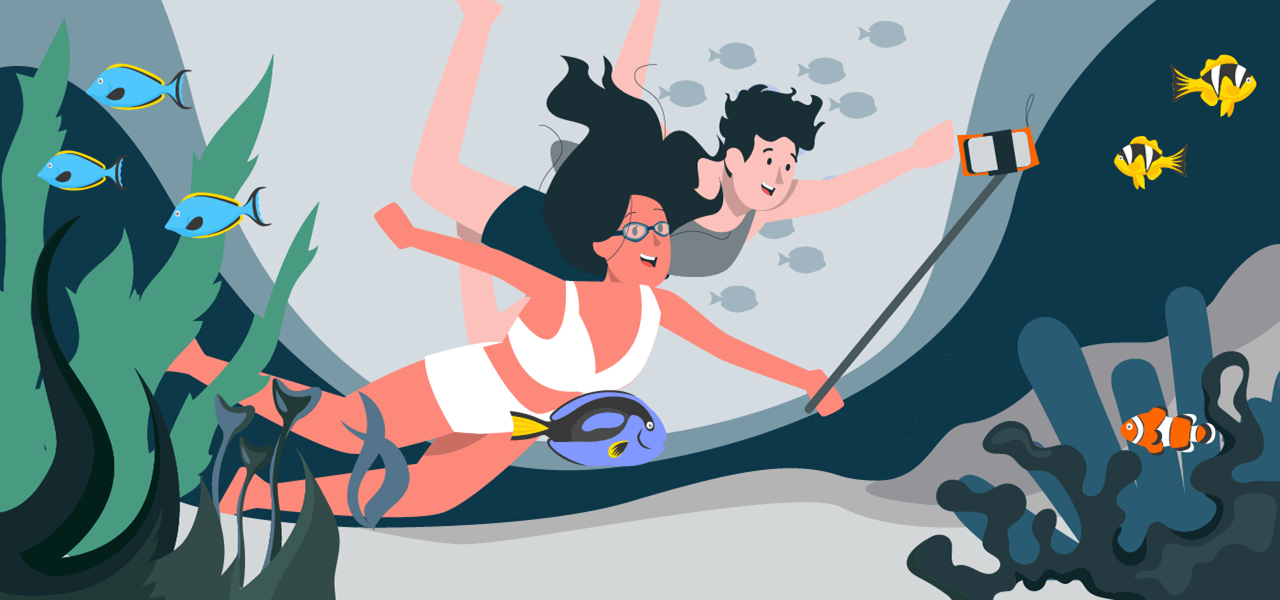 Zwei Personen tauchen mit Taucherbrille und wasserdichter Kamera durch ein Korallenriff. Um sie schwimmen bunte Fische und Pflanzen.