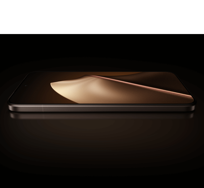 Ein schwarzes Smartphone liegt flach auf einer dunklen, reflektierenden Oberflche vor schwarzem Hintergrund. Auf dem Display ist ein goldbraunes, wellenfrmiges abstraktes Muster zu sehen. Das Gert hat abgerundete Ecken und einen dnnen Rahmen.